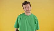 A Young Man in a Green Tshirt Poses on a Yellow Background A Man Stands in Front of the Camera and