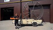 Mechanics ride a car using a giant hamster wheel