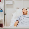 Man in Hospital Bed Holding Paper