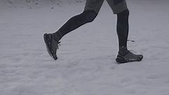 Unknown male jogging in winter in running shoes on snow. Running in all kinds of conditions. Legs of jogger in freezing snowy weather. Every day to run and exercise, no matter what season.