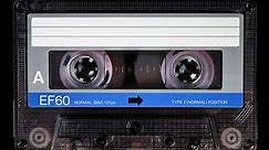 Audio cassette tape in use for sound recording in the tape recorder. A vintage, blue color, brand new blank labelled music cassette playing back in a deck player. Static video camera shot. Close up 4K