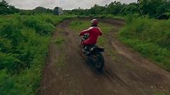 Extreme close follow motocross dirt track moto riding jumping male speed race on winding sand dirt path at tropical jingle aerial view. FPV sport drone motorbike speed adrenaline ride offroad trail 4k