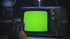 Changing Channels TV Green Screen Remote Control Retro Television Zoom In. Remote control changing channels on an old vintage green screen television, zoom in.