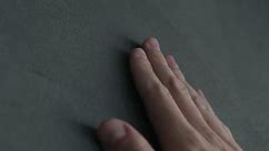 Slow motion man hand touches decorative concrete finish