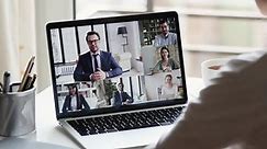 Webcam company team meeting concept. Remote employee conferencing boss and coworkers in online group virtual chat using pc video call app working from home office. Over shoulder laptop screen view