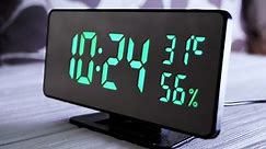 Digital Clock Showing Time on Green Display 10:24 AM, Temperature, Air Humidity. Modern mirror clock, alarm clock with a thermometer, hydrometer standing on a desk on white background. Time concept.