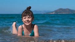 Happy child on the sea beach. A funny little girl enjoy the time in the warm sea water against tropical bay.