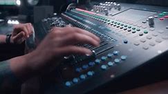 Audio engineer uses mixing console, remote control for adjusting sound, audio mixer. Musician changes the volume level, creates music with modern equipment. Sound recording studio. Music production.