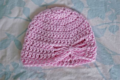 pink knitted hat laying  top   blue  white bed sheet