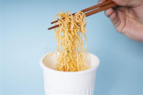 Hand Of Person Using Wooden Chopstick Eating Instant Noodle From A Cup