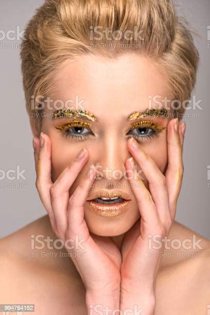 beautiful girl with golden glittering makeup touching face isolated on