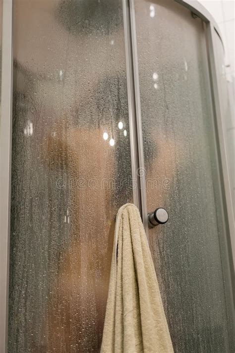 beautiful woman in the shower behind glass with drops woman in the