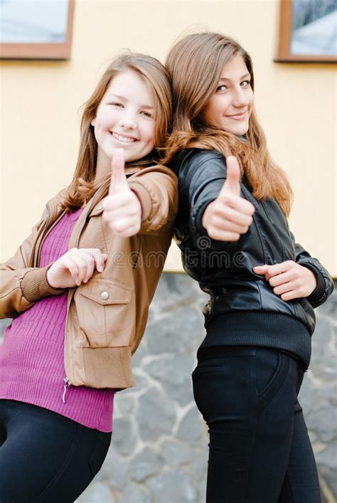 Two Pretty Happy Teen Girl Friends Laughing And Pointing To