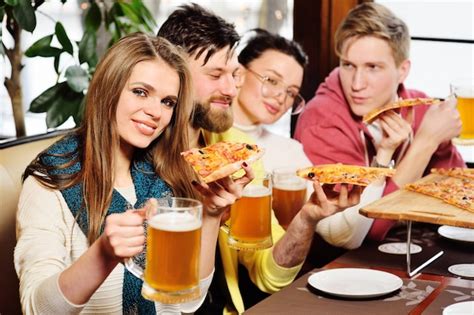 grupo de amigos comiendo pizza  bebiendo cerveza en el bar  en la