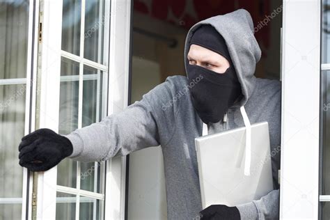 burglar breaking  house  stealing laptop computer stock photo