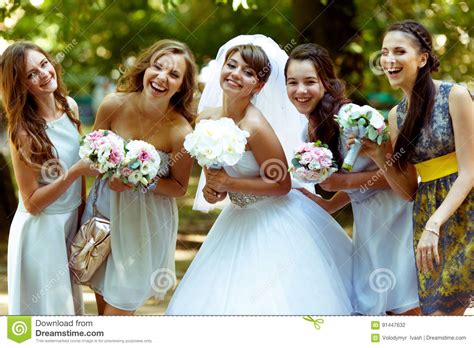 la sposa sorridente posa con le damigelle d onore felici con i bouqets in loro fotografia stock