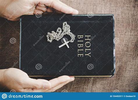 Hands Folded In Prayer On A Holy Bible In Church Concept