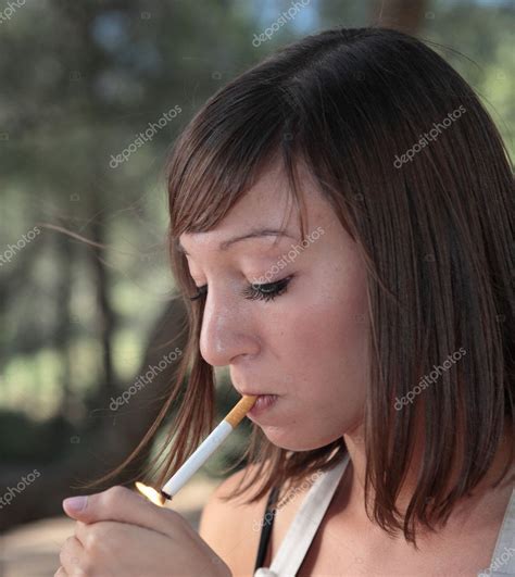 retrato de una hermosa joven encendiendo un cigarrillo al aire libre