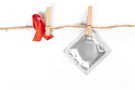 Red Ribbon And Condom With Clothespins Hanging On A Rope Creative