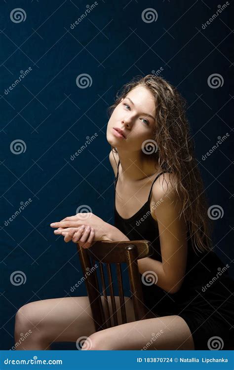 a girl with beautiful bright skin sits on a wooden chair wet curly