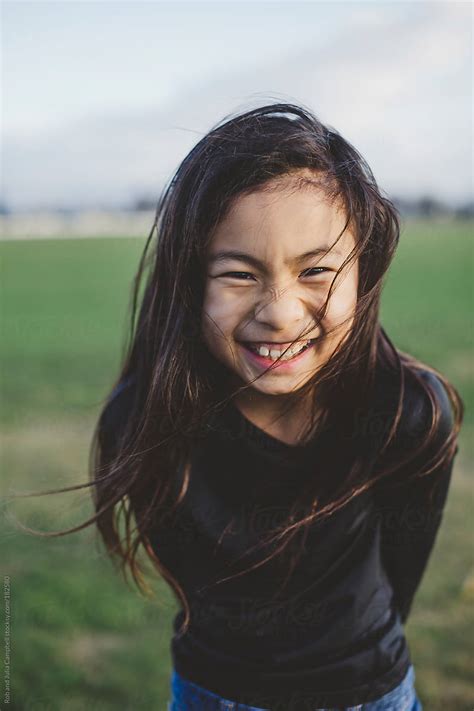 cute elementary school aged asian girl happy in windy field by