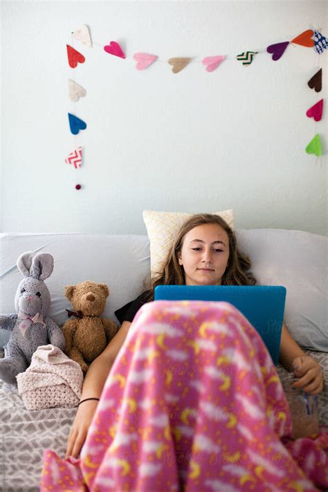Teenage Or Tween Girl Sitting In Her Bedroom Watching Tv On Her Laptop