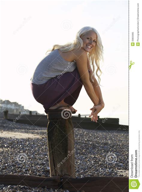 Cheerful Woman Crouching On Wooden Pole Royalty Free Stock