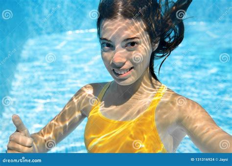 girl swims in swimming pool underwater happy active teenager dives and