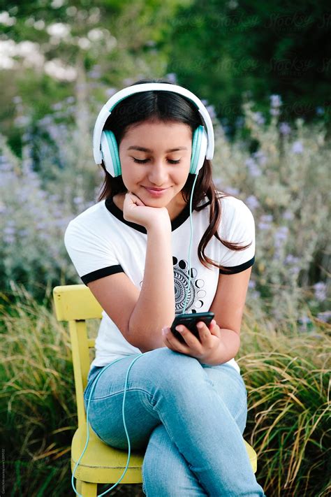 pretty teenage girl wearing headset and holding mobile phone by
