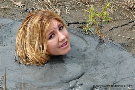 A Woman Laying In The Mud With Her Head Sticking Out And Eyes Wide Open