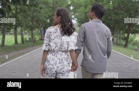 filipino asian couple holding hands while walking together in a long