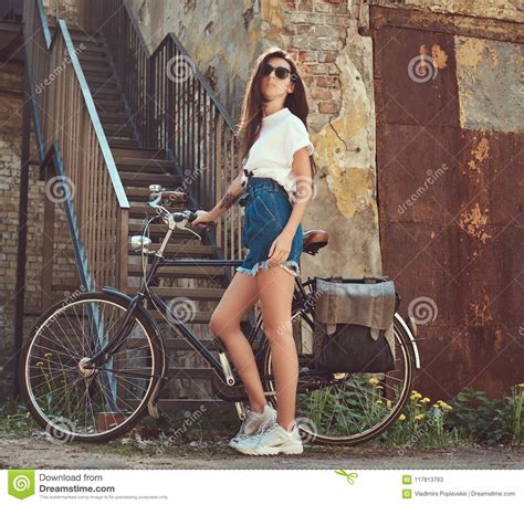 slim girl in short denim shorts white t shirt and sunglasses posing