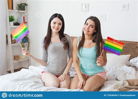 Lesbian Couple In Bedroom At Home Sitting Holding Lgbt