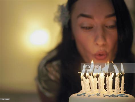 woman blowing out candles on birthday cake focus on candles photo