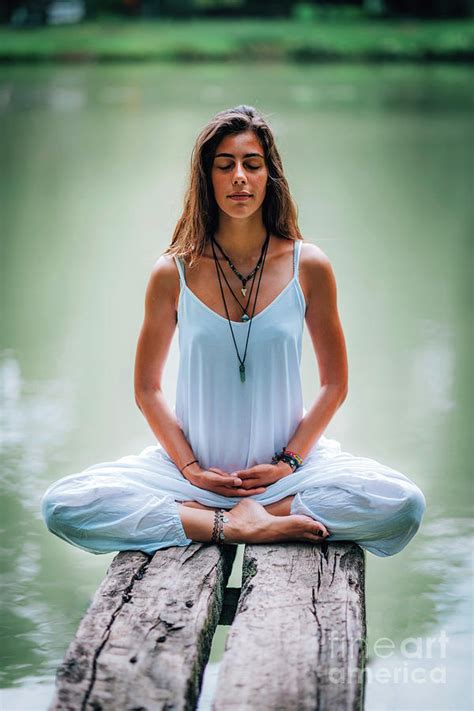 woman meditating by a lake photograph by microgen images science photo