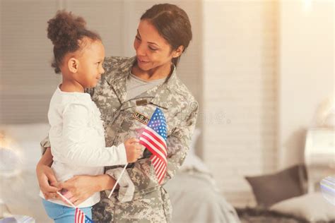 Military Mother Talking To Daughter While Hugging Her Stock Image