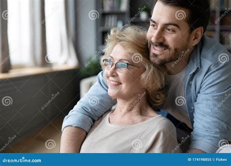 hopeful mature mother and adult son visualizing at home stock image