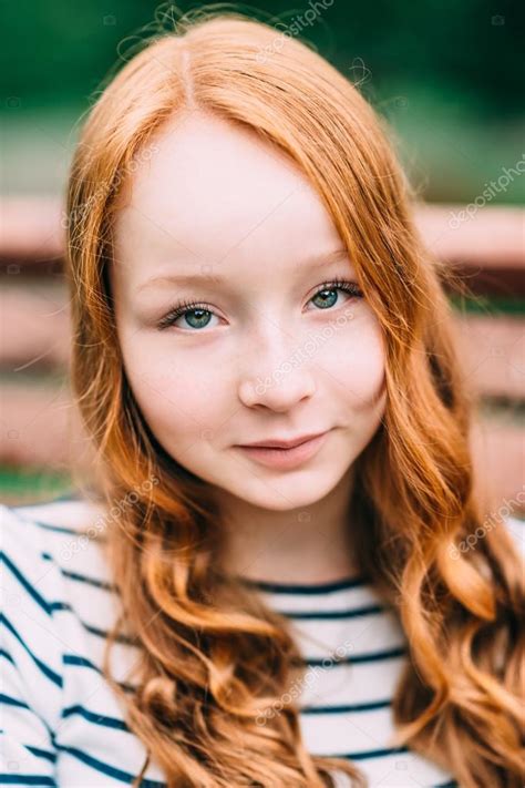 close up portrait of pretty smiling girl with long curly red hair in summer park outdoor