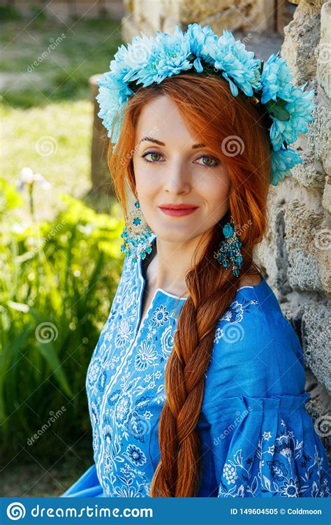 beautiful red haired girl in a blue dress ukrainian with a wreath on
