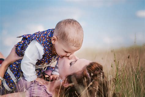 beautiful mother lying on a field hugging and kissing her daughter by