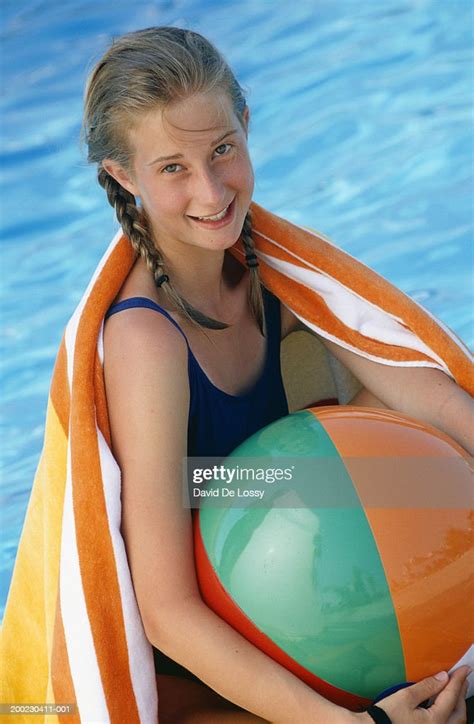 Girl With Towel On Shoulders Sitting With Beach Ball By Pool High Res