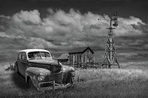 vintage automobile and wooden barn with windmill in black and white