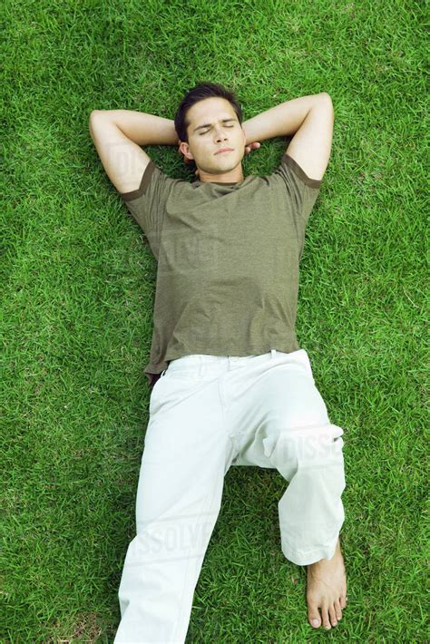 young man lying  grass  eyes closed high angle view stock