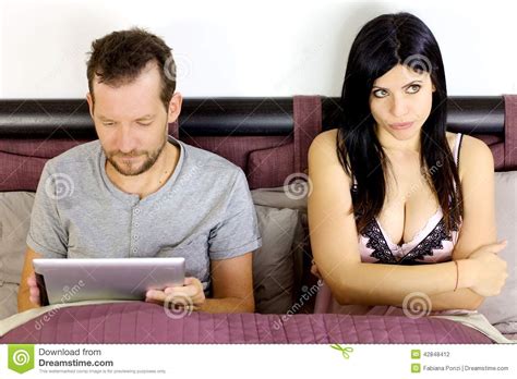 beautiful sexy woman bored about husband playing with tablet stock