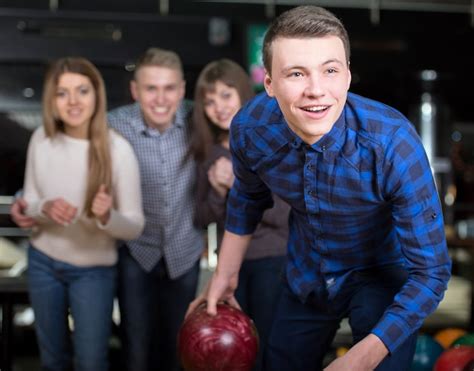 Premium Photo Group Of Four Friends In A Bowling Alley Having Fun