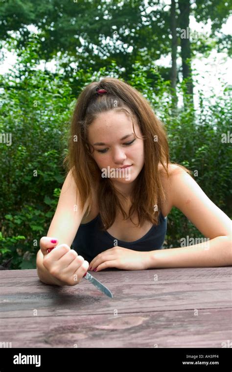 Teen Girl Sitting At A Picnic Table And Playing With A Knife Model