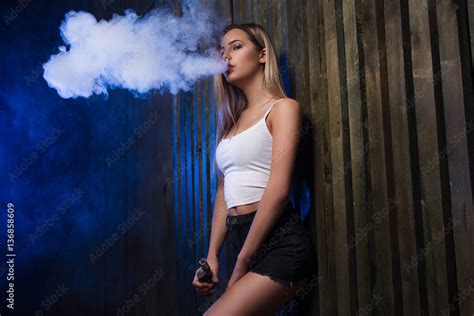 foto stock cloud of smoke sexy girl vapeing and smoking electronic