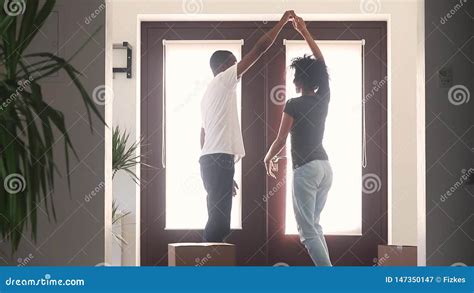 Happy African Couple First Time Home Buyers Dancing In Hallway Stock