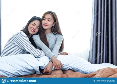 two asian lesbian women hug together in bedroom couple