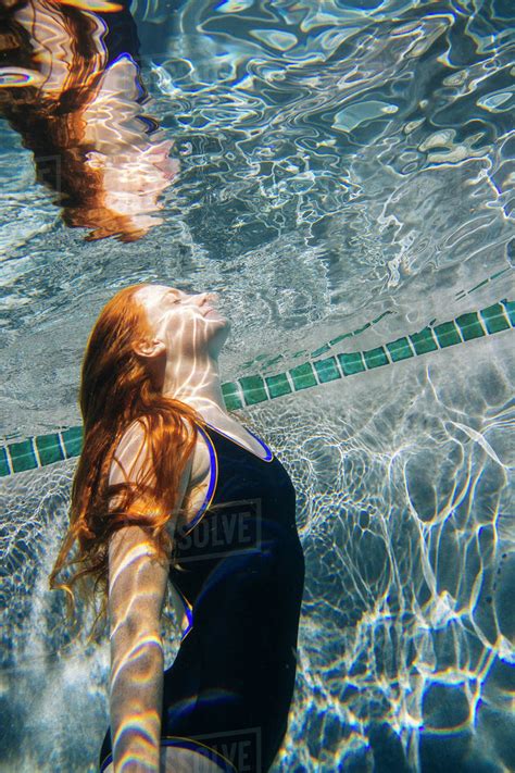 teenage girl  red hair swimming underwater  pool stock photo dissolve